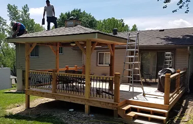 Contractors finishing roof of backyard gazebo on rebuilt deck