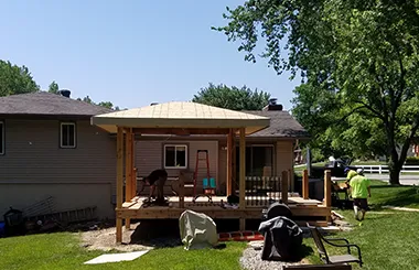 Construction crew installing gazebo roof on new deck