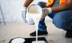 Professional painting contractor in Omaha pouring white paint into tray for interior painting project