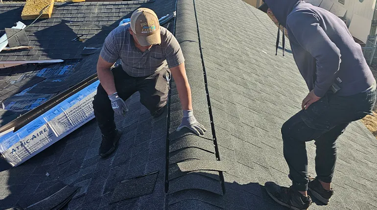Two contractors performing roofing repair by installing shingles on a residential roof.