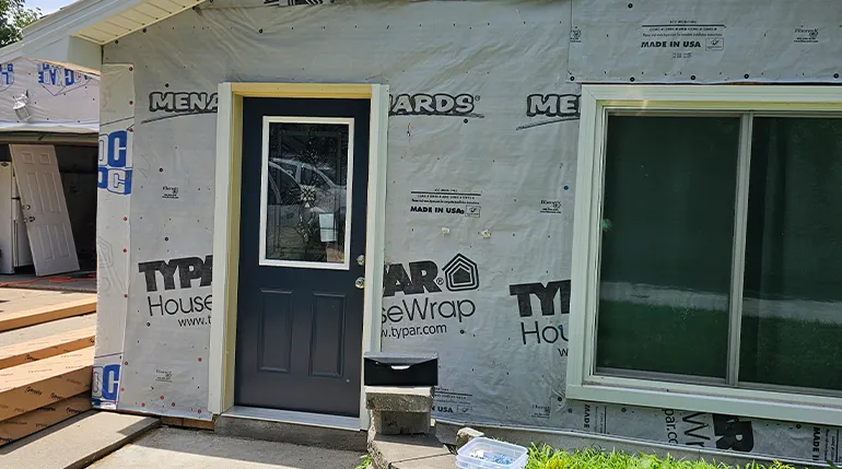 After windows and doors Omaha project with new entry door, siding, and replacement window installed.