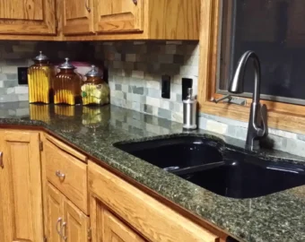 A classic Omaha kitchen with dark granite countertops, oak cabinets, and a black undermount sink featured in a kitchen remodel cost Omaha project.