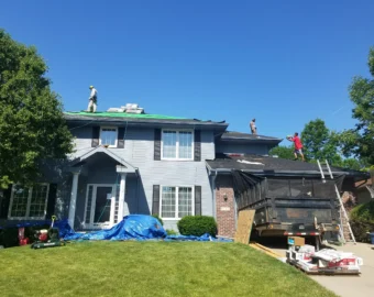 Roofers installing new shingles on a two story home as part of a roof insurance claim Omaha NE replacement.